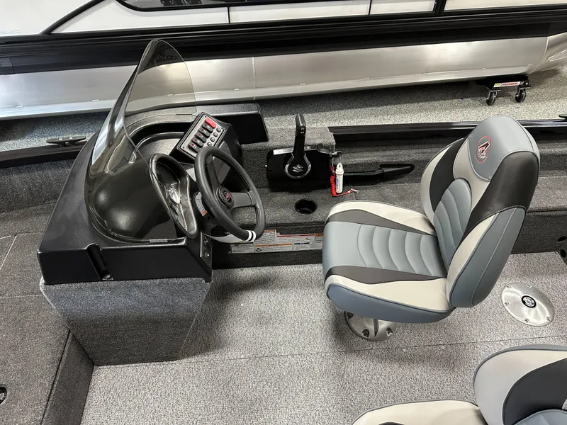 Slide: The Image of 2024 Alumacraft Classic 165 SC boat interior with steering wheel and cushioned seat. - 7