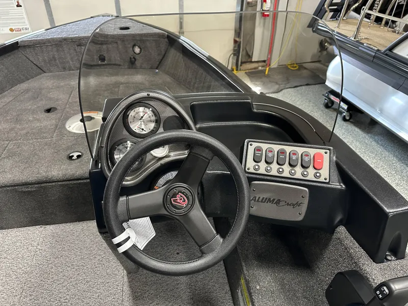 Slide: The Image of 2024 Alumacraft Classic 165 SC boat dashboard with steering wheel and control panel. - 8