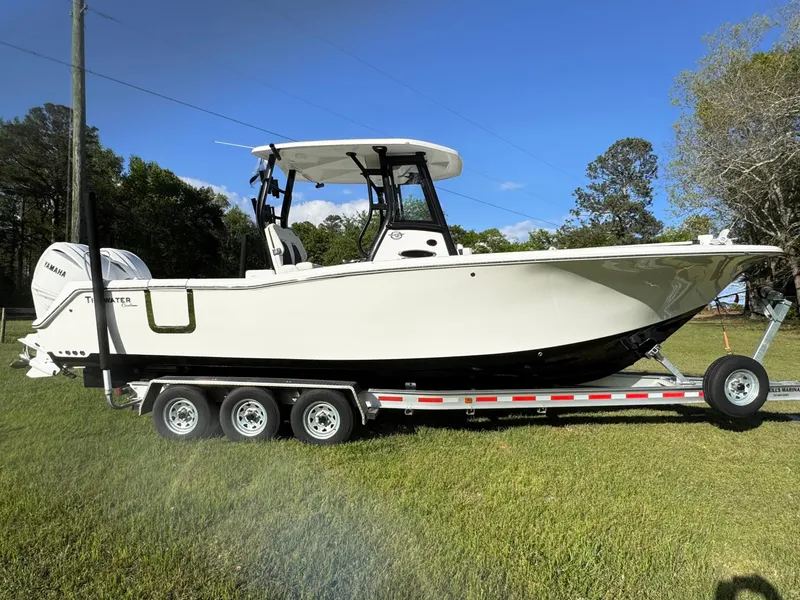 The Image of 2024 Tidewater 292 CC Adventure boat on trailer, parked on grass under clear blue sky. - 1