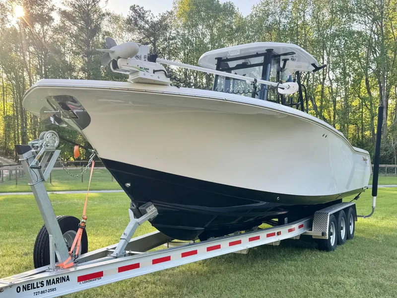 Slide: The Image of 2024 Tidewater 292 CC Adventure boat on trailer, parked on grass with trees in background. - 10