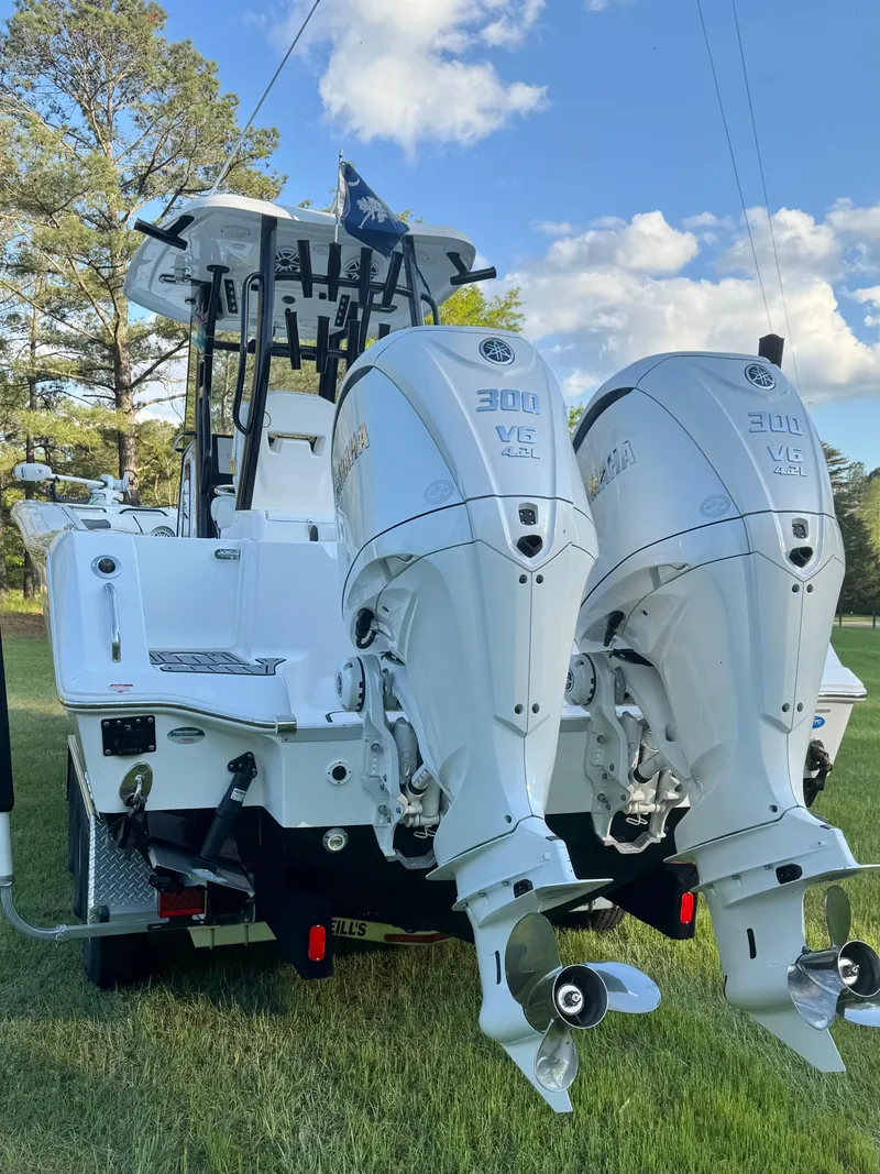 Slide: The Image of 2024 Tidewater 292 CC Adventure boat with dual outboard engines on grassy field. - 11