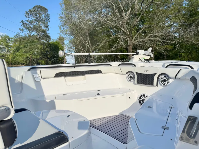 Slide: The Image of 2024 Tidewater 292 CC Adventure boat interior with seating and speakers, surrounded by trees. - 13