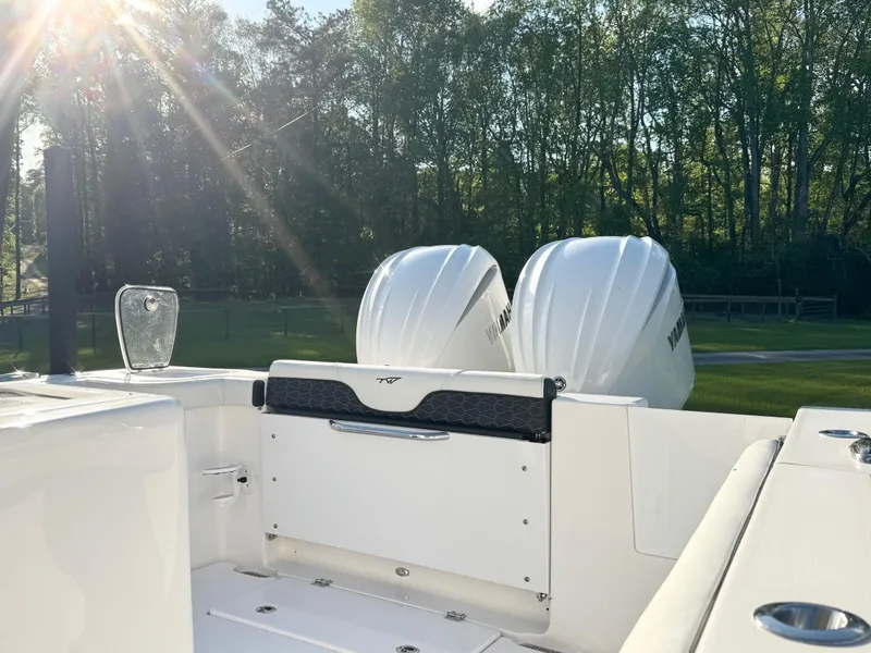 Slide: The Image of 2024 Tidewater 292 CC Adventure boat with dual engines, sunlit deck, and forest backdrop. - 16