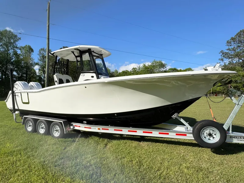 Slide: The Image of 2024 Tidewater 292 CC Adventure boat on trailer, parked on grass under clear sky. - 17
