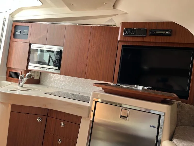 Slide: The Image of 2019 Grady-White Express 330 interior with kitchenette, microwave, fridge, and TV. - 10