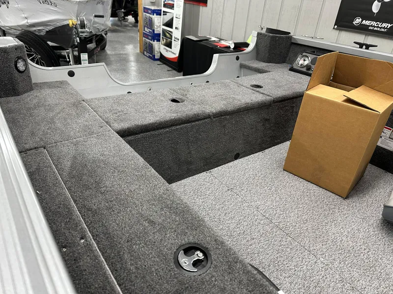 Slide: The Image of 2024 Alumacraft Classic 165 Tiller boat interior, featuring seating and control panel in showroom. - 16