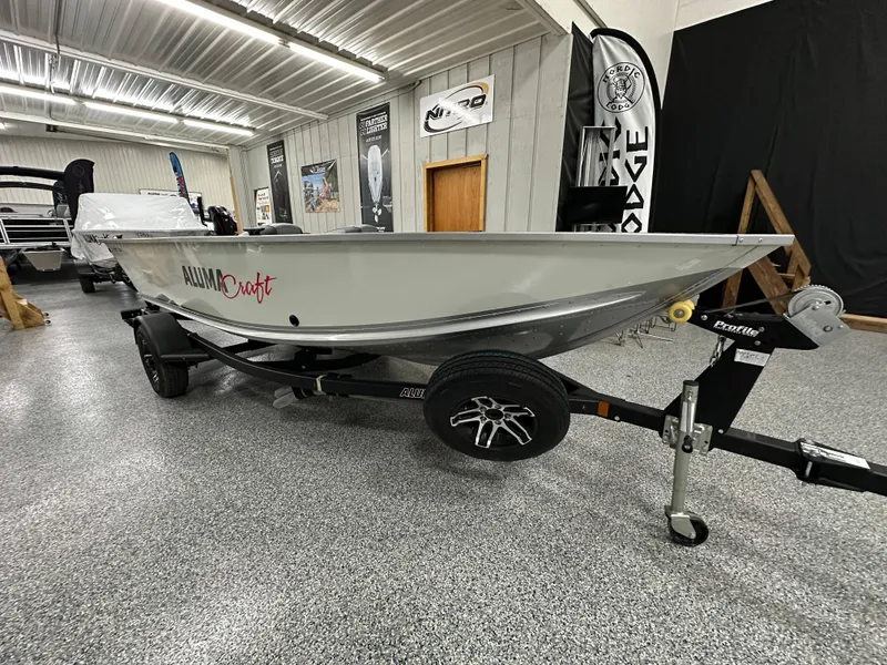 Slide: The Image of 2024 Alumacraft Classic 165 Tiller boat in showroom, rear view, gray interior. - 3