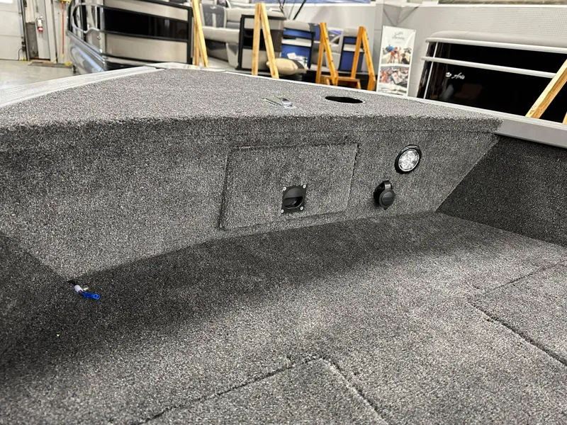 Slide: The Image of 2024 Alumacraft Classic 165 Tiller boat interior with carpeted deck and control panel. - 6