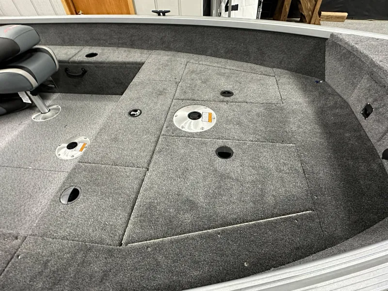 Slide: The Image of 2024 Alumacraft Classic 165 Tiller boat interior with gray carpeted deck and seating. - 8