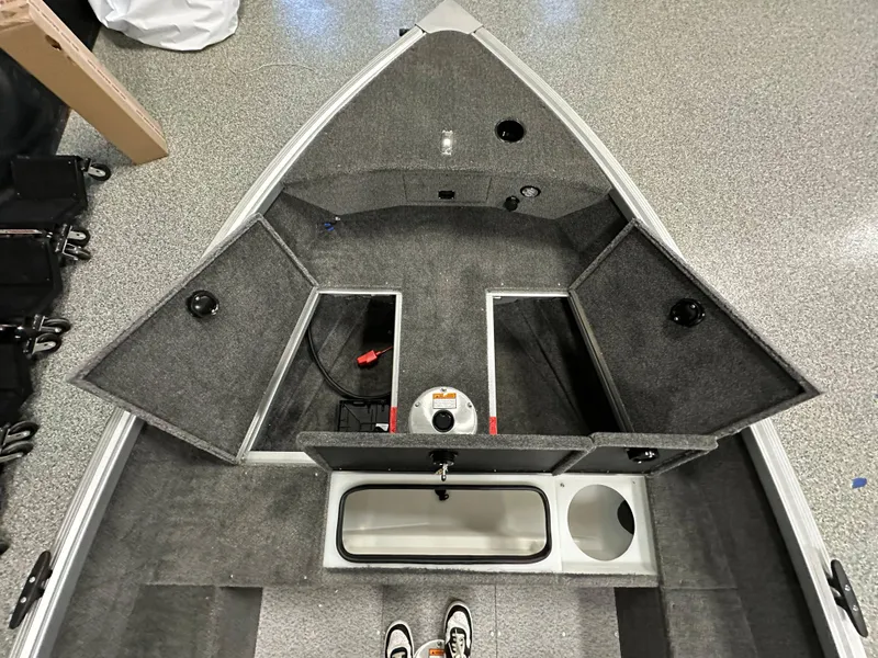 Slide: The Image of 2024 Alumacraft Classic 165 Tiller interior with open storage compartments and carpeted flooring. - 6