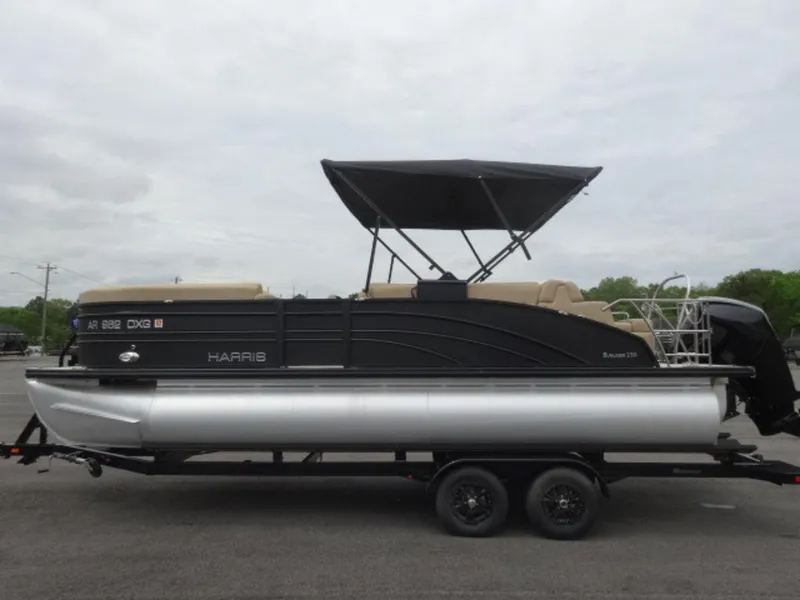 Slide: The Image of 2023 Harris Sunliner 230 pontoon boat on trailer, featuring a sleek design and canopy. - 21