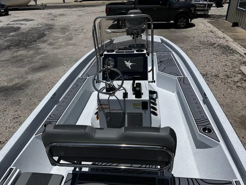 Slide: The Image of 2025 Xpress H22B boat interior with steering console and seating, parked outdoors. - 7