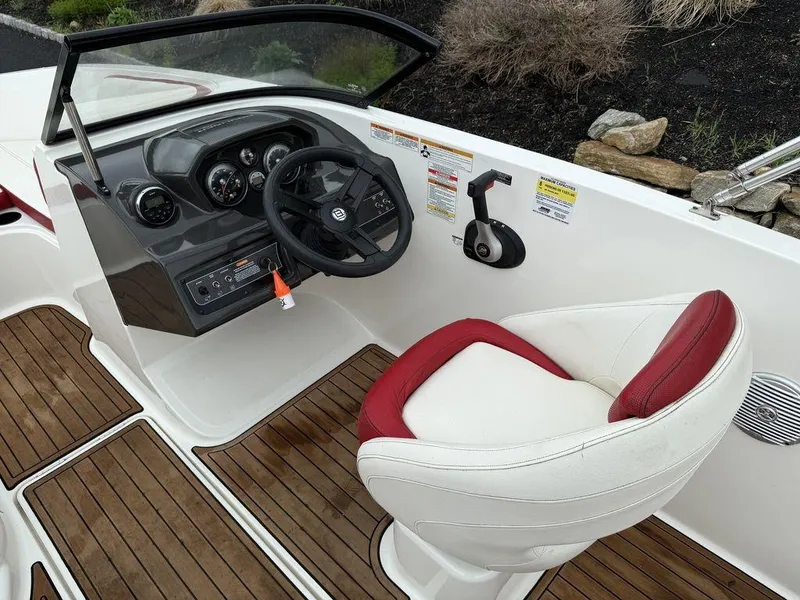 Slide: The Image of 2016 Bayliner VR5 Bowrider cockpit with steering wheel, red and white seat, and wood flooring. - 12