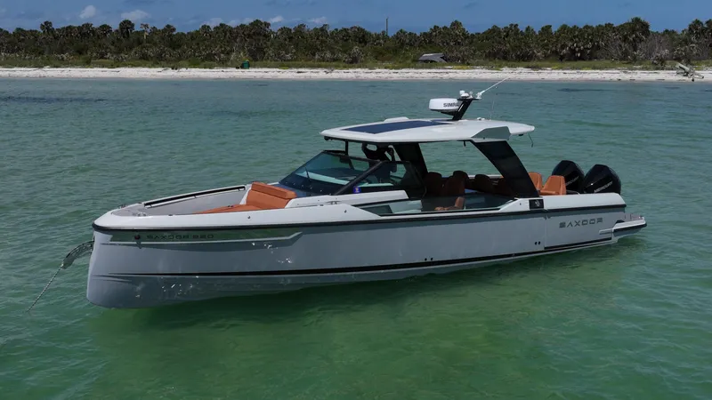Slide: The Image of 2023 Saxdor 320 GTO boat in calm turquoise waters near a sandy beach. - 1