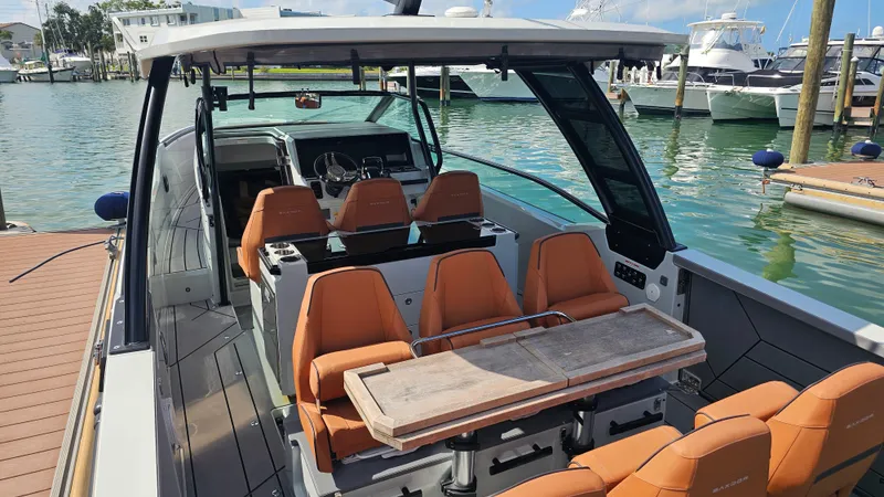 Slide: The Image of 2023 Saxdor 320 GTO boat with orange seating and wooden table, docked at a marina. - 12