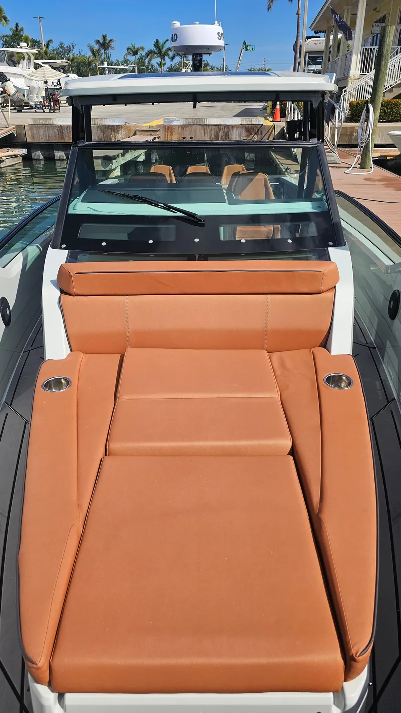 Slide: The Image of 2023 Saxdor 320 GTO boat with orange seating, docked near a waterfront home. - 19