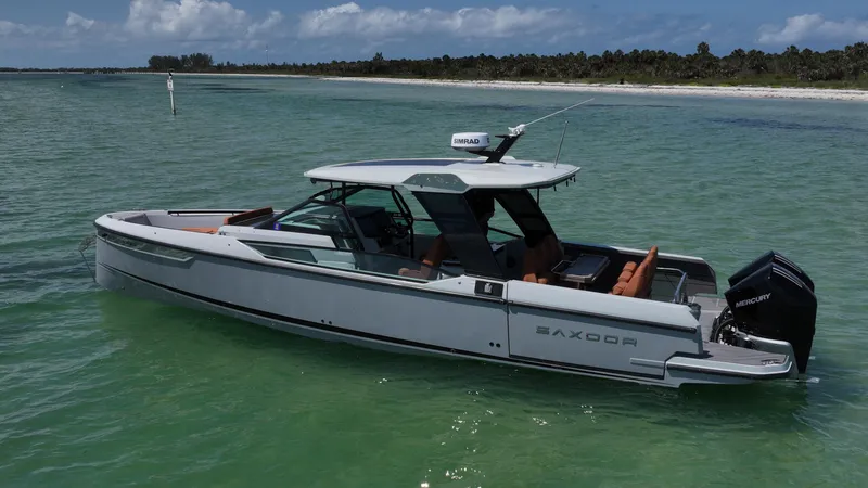 Slide: The Image of 2023 Saxdor 320 GTO boat on clear water near a sandy shoreline. - 2