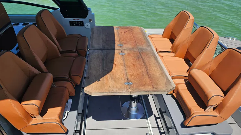 Slide: The Image of 2023 Saxdor 320 GTO boat interior with brown leather seats and wooden table. - 25