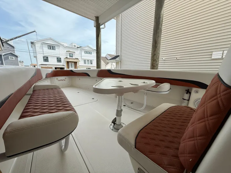 Slide: The Image of 2007 Carrera Boats 36 Center Console with brown leather seating and table, docked near houses. - 12