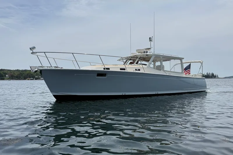 Slide: The Image of 2016 MJM 40z Downeast yacht on calm water, displaying sleek design and American flag. - 6