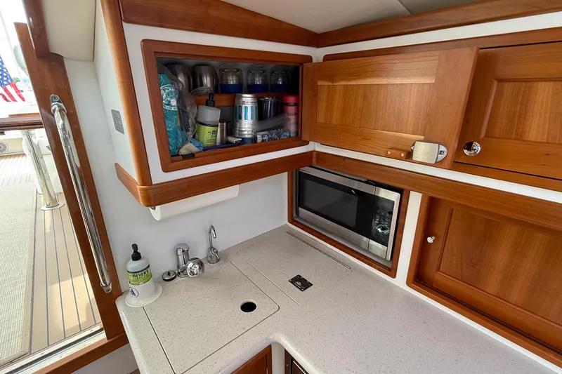 Slide: The Image of 2016 MJM 40z Downeast yacht galley with wooden cabinets, microwave, and countertop sink. - 36