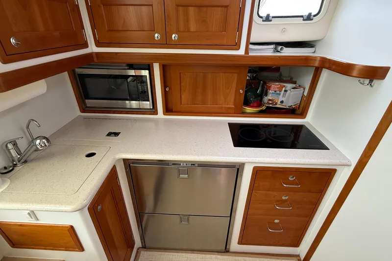 Slide: The Image of 2016 MJM 40z Downeast yacht kitchen with stove, microwave, and wooden cabinetry. - 29