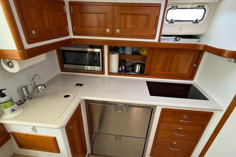 Slide: The Image of 2016 MJM 40z Downeast yacht kitchen with wooden cabinets, stove, sink, and microwave. - 30