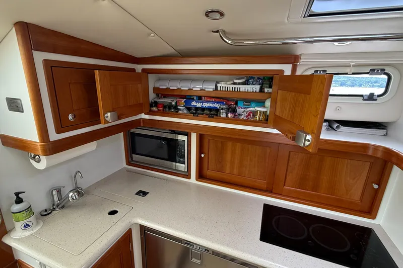 Slide: The Image of 2016 MJM 40z Downeast yacht kitchen with wooden cabinets, microwave, and modern appliances. - 28