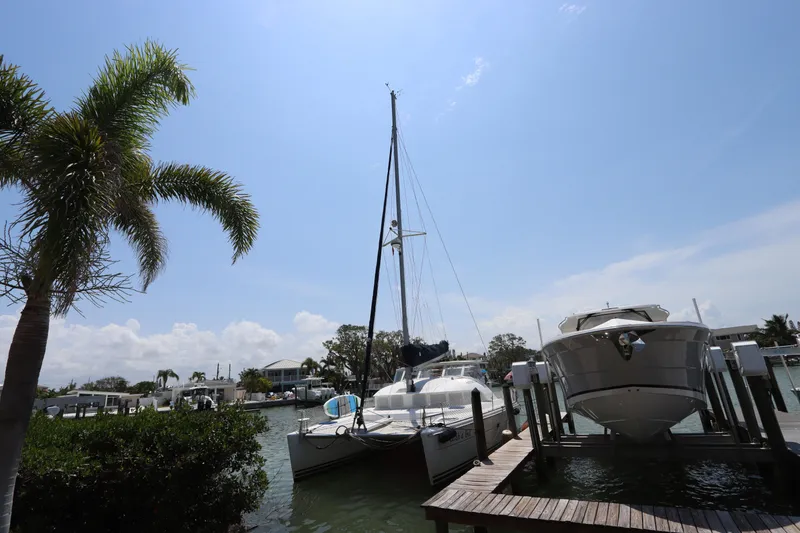 Slide: The Image of Lagoon 380 catamaran docked beside a motorboat under a clear blue sky. - 1