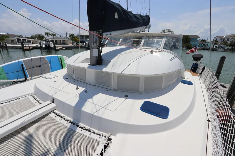 Slide: The Image of 2001 Lagoon 380 catamaran docked, featuring spacious deck and trampoline netting. - 13