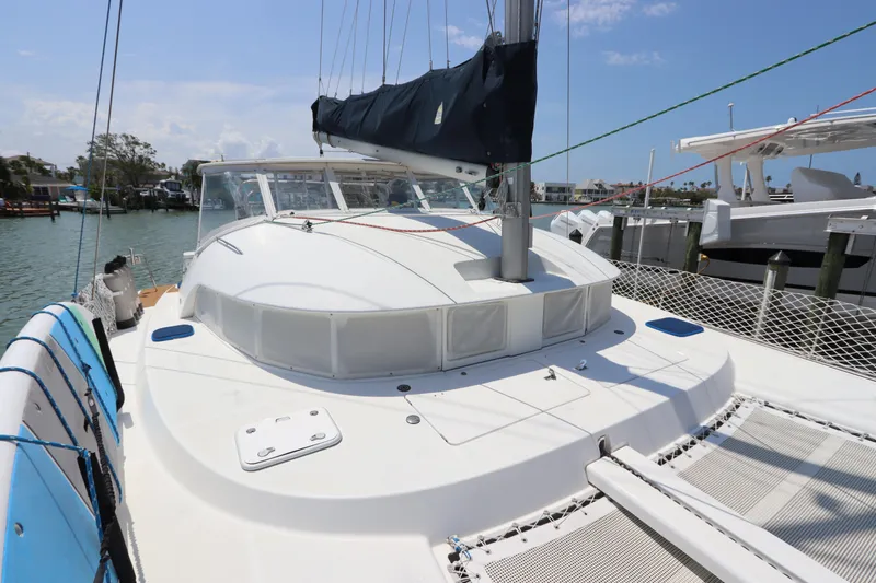 Slide: The Image of 2001 Lagoon 380 catamaran docked, featuring spacious deck and netting, under clear skies. - 15