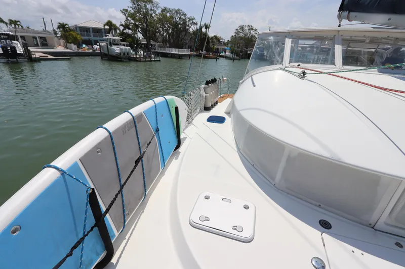 Slide: The Image of 2001 Lagoon 380 catamaran deck with paddleboard, docked in a serene marina setting. - 16