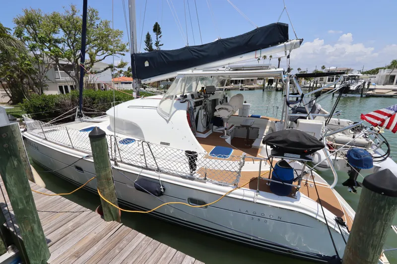 Slide: The Image of 2001 Lagoon 380 catamaran docked at marina, featuring spacious deck and modern design. - 2
