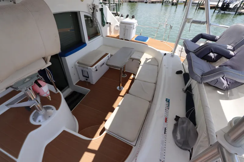 Slide: The Image of Spacious deck of 2001 Lagoon 380 catamaran with seating and table, docked by the water. - 24