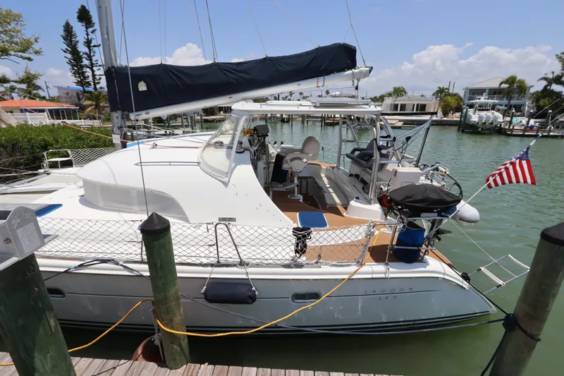 Slide: The Image of 2001 Lagoon 380 catamaran docked in a marina, featuring a sleek design and American flag. - 3