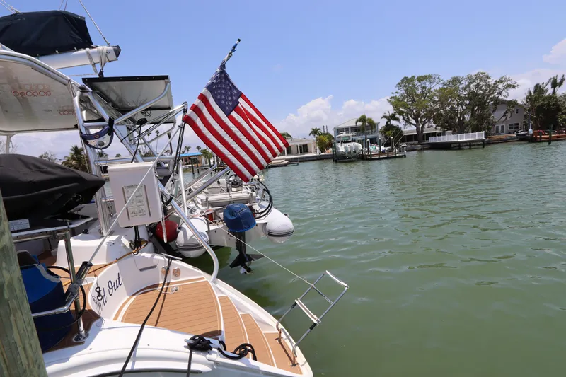 Slide: The Image of Lagoon 380 catamaran docked, displaying American flag, calm waters, sunny day, 2001 model. - 4