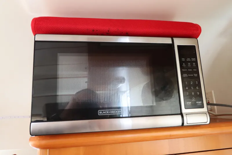 Slide: The Image of Black and Decker microwave with red cover on wooden shelf, Lagoon 380, 2001 model. - 49