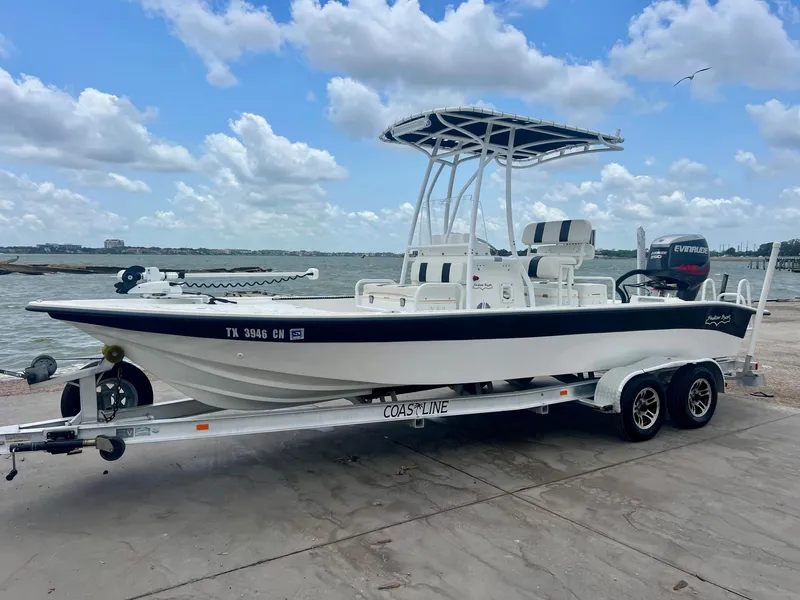 Slide: The Image of 2015 Shallow Sport 24 Modified V boat on trailer by the water, under a cloudy sky. - 1