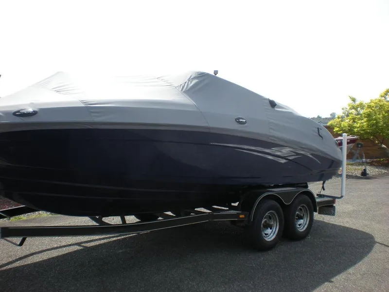 Slide: The Image of 2011 Yamaha AR210 boat covered on a trailer, parked outdoors. - 0