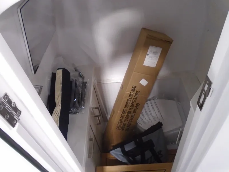 Slide: The Image of Storage compartment with various items, including a large cardboard box, on a Jupiter 32 boat. - 26