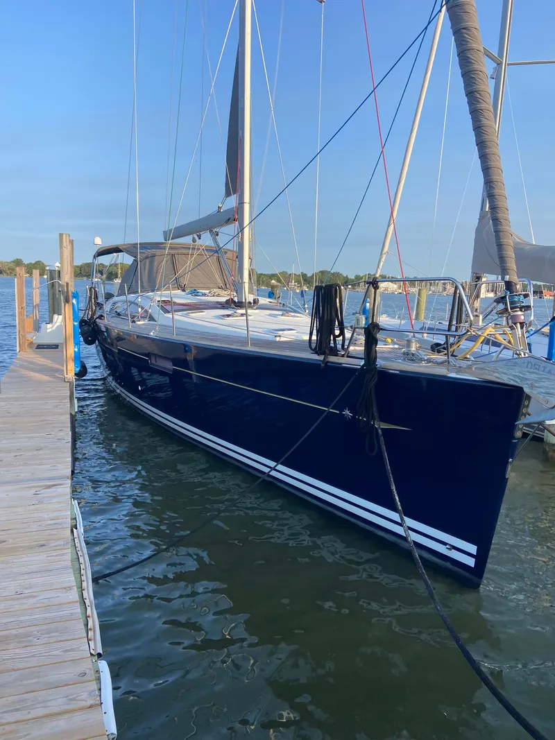 Slide: The Image of 2016 Jeanneau 58 sailboat docked at marina, blue hull, clear sky background. - 2