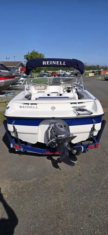 Slide: The Image of 2003 Reinell 185 boat with outboard motor, parked on a sunny day. - 5