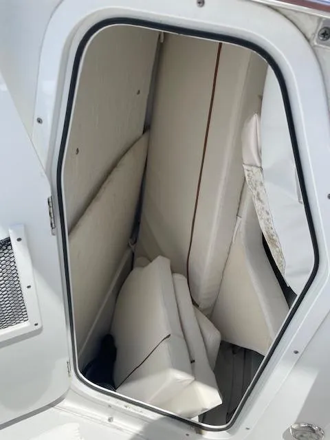 Slide: The Image of Storage compartment in a 2022 Sea Hunt Ultra 229 boat, featuring white interior cushions. - 13