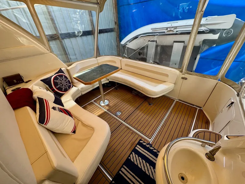 Slide: The Image of 2000 Sea Ray 310 Sundancer interior with seating, table, and nautical-themed cushions. - 10