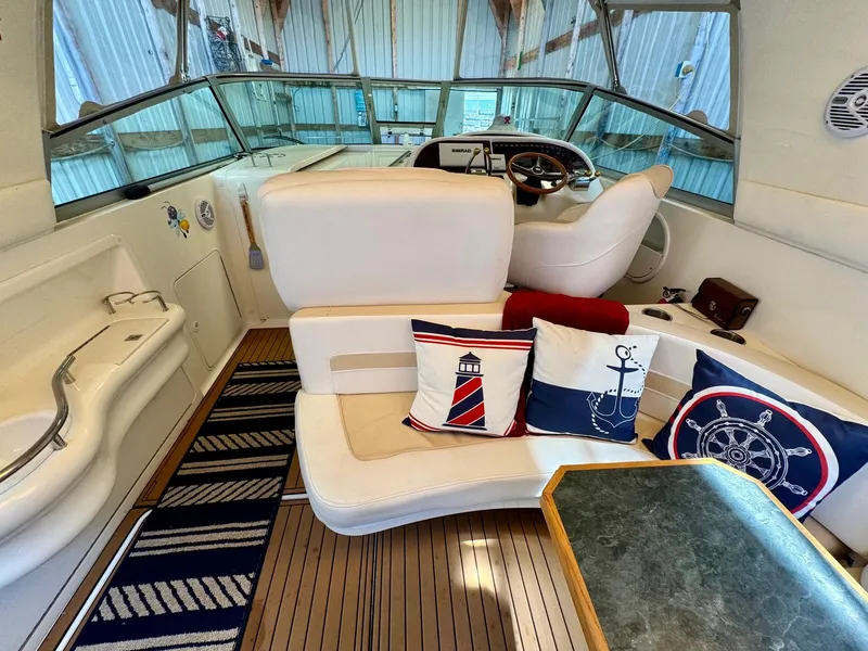 Slide: The Image of Interior of 2000 Sea Ray 310 Sundancer with nautical-themed cushions and wooden flooring. - 13