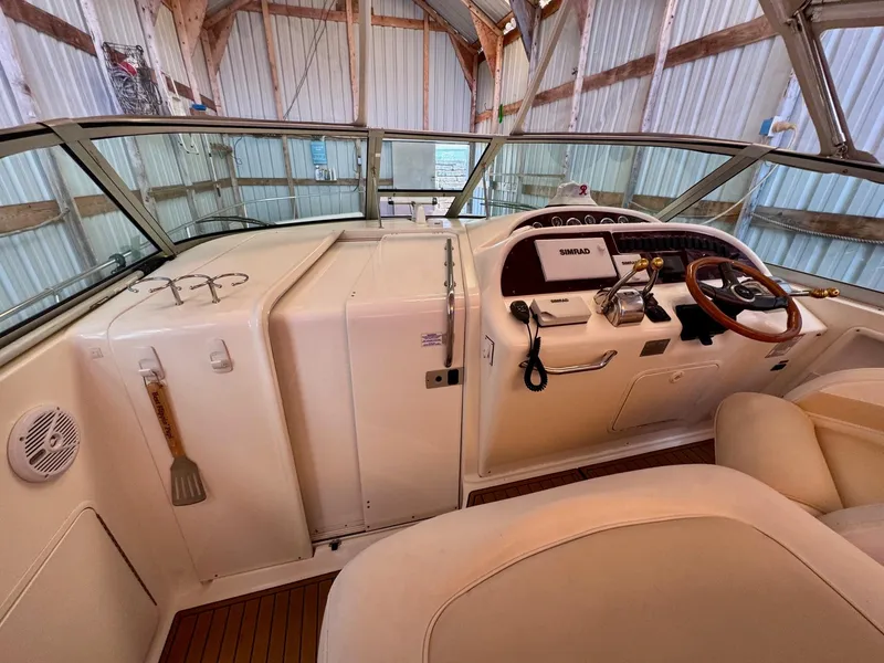 Slide: The Image of 2000 Sea Ray 310 Sundancer helm with steering wheel and control panel in a covered dock. - 16