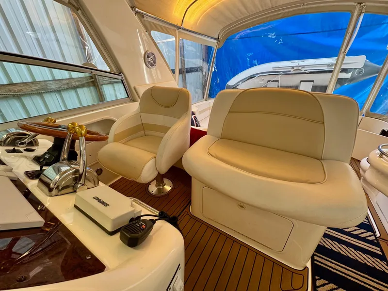 Slide: The Image of 2000 Sea Ray 310 Sundancer cockpit with beige seating and wooden flooring. - 19