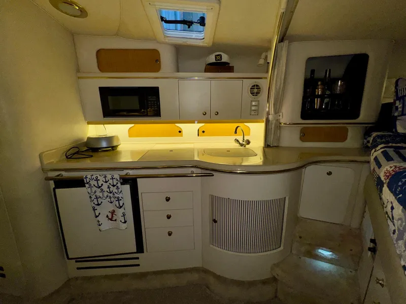 Slide: The Image of 2000 Sea Ray 310 Sundancer cabin kitchen with microwave, sink, and storage cabinets. - 27