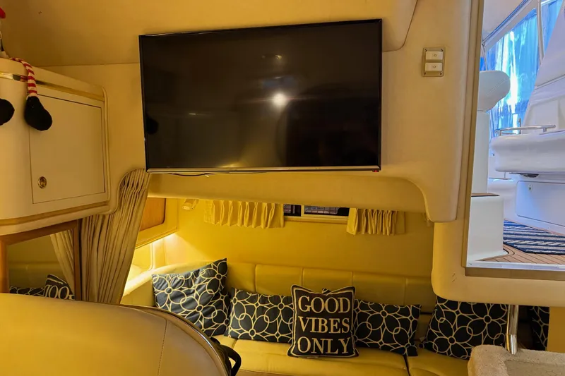 Slide: The Image of Interior of 2000 Sea Ray 310 Sundancer with TV, cozy seating, and "Good Vibes Only" pillow. - 30