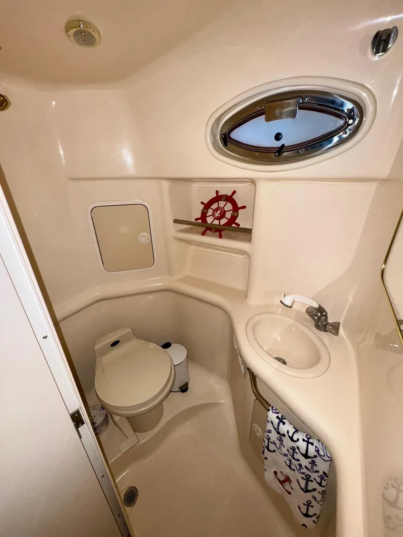 Slide: The Image of 2000 Sea Ray 310 Sundancer bathroom with porthole, toilet, sink, and nautical decor. - 33